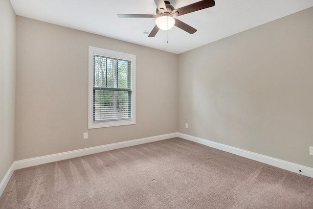 carpeted spare room featuring baseboards and a ceiling fan