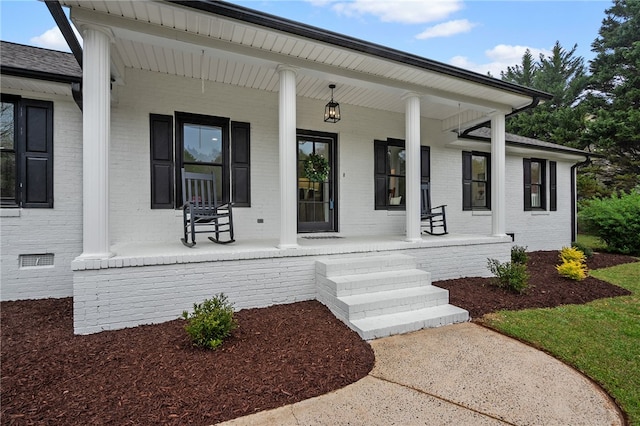 doorway to property with covered porch and brick siding