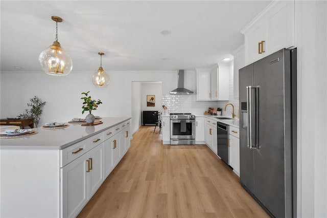 kitchen with a sink, light countertops, wall chimney range hood, and stainless steel appliances