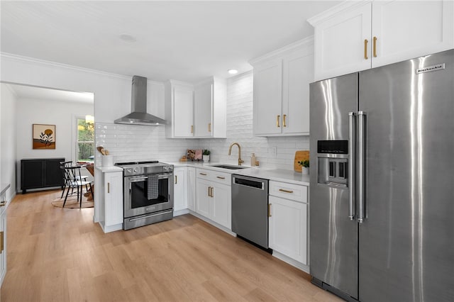kitchen featuring light countertops, a sink, wall chimney exhaust hood, and appliances with stainless steel finishes