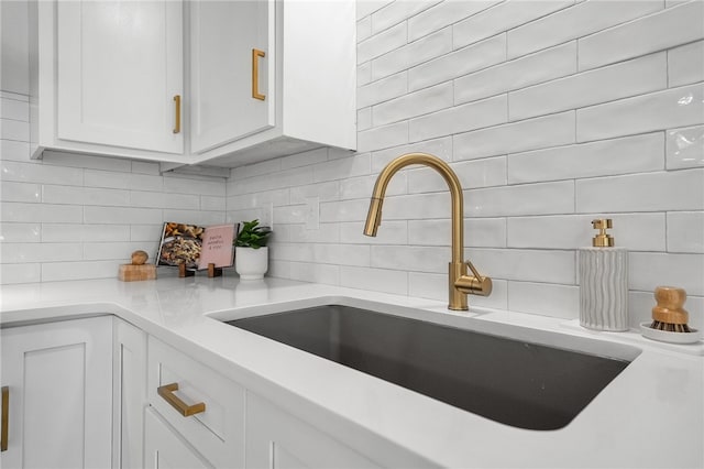 kitchen with decorative backsplash, white cabinetry, and a sink