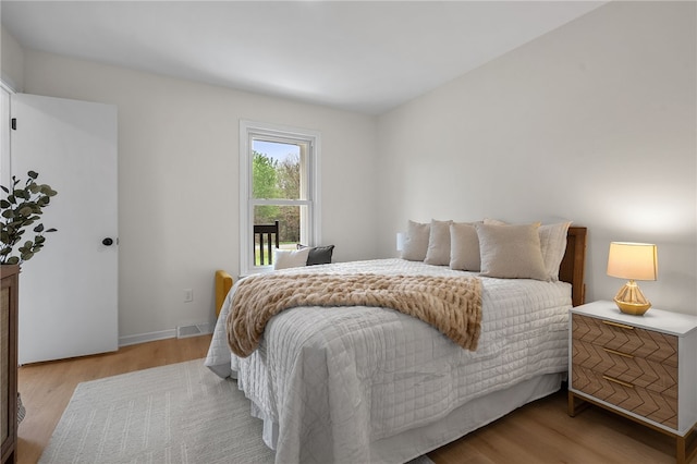 bedroom featuring baseboards, visible vents, and wood finished floors