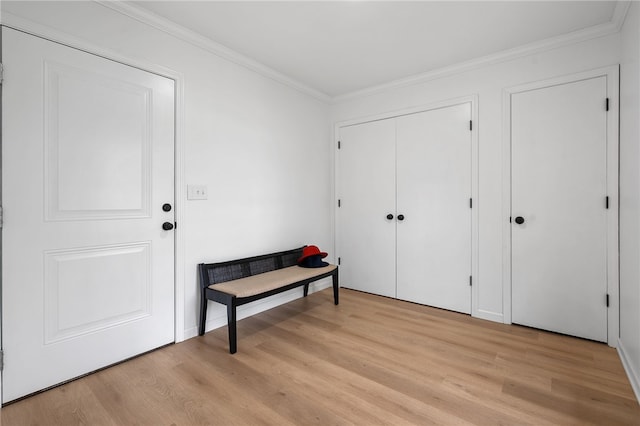 entryway with light wood-style floors and ornamental molding