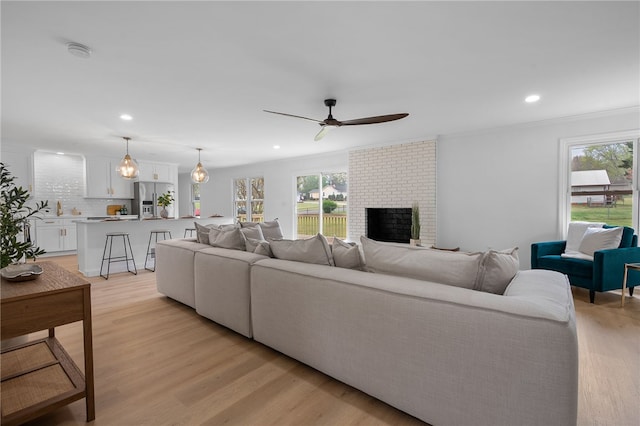 living area featuring a fireplace, light wood-style flooring, recessed lighting, and a ceiling fan