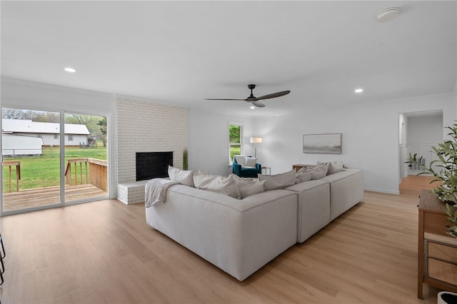 living area with a ceiling fan, crown molding, and light wood-type flooring