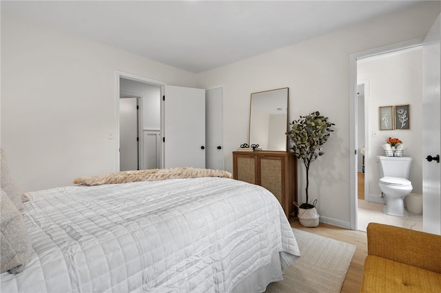 bedroom with light wood-style flooring, connected bathroom, and baseboards