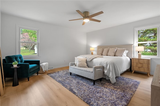 bedroom featuring multiple windows, light wood-style floors, and ceiling fan