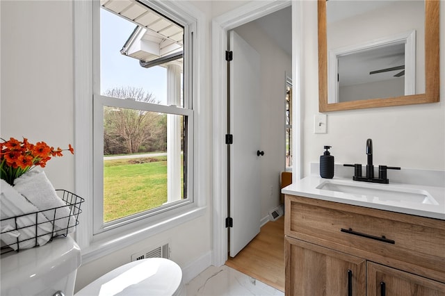 half bathroom featuring vanity, toilet, baseboards, marble finish floor, and visible vents