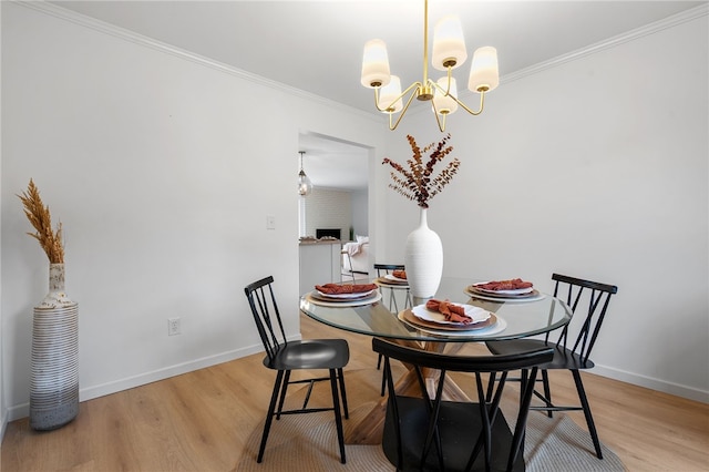 dining room with baseboards, wood finished floors, ornamental molding, and a chandelier