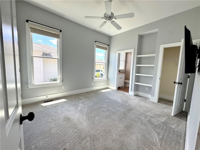 unfurnished bedroom with connected bathroom, carpet floors, baseboards, and multiple windows