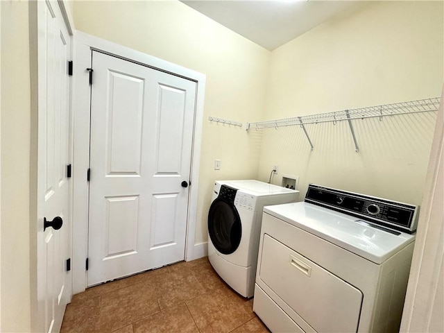 laundry room with light tile patterned floors, baseboards, washing machine and dryer, and laundry area