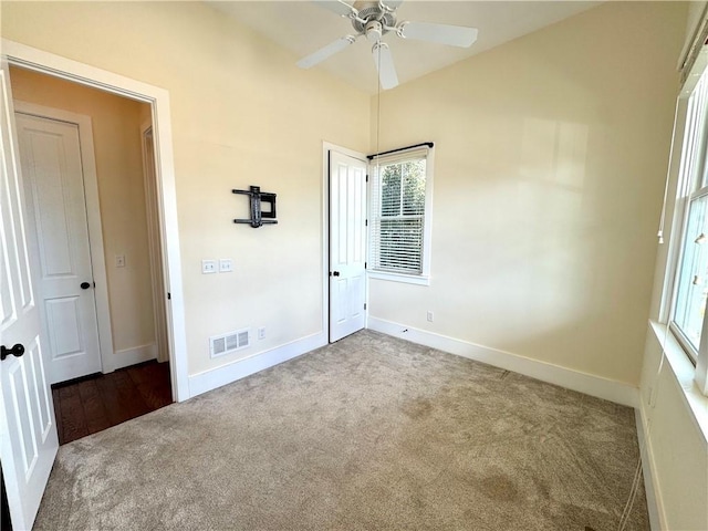 unfurnished bedroom with baseboards, multiple windows, visible vents, and carpet