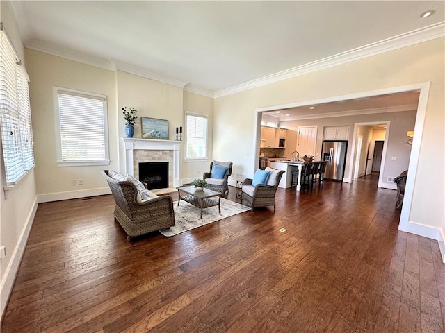 living room with a fireplace, crown molding, baseboards, and dark wood finished floors