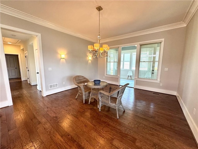 dining space featuring visible vents, wood finished floors, ornamental molding, and a notable chandelier