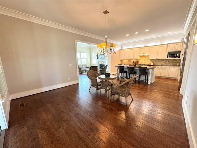 dining area with recessed lighting, baseboards, dark wood-style flooring, ornamental molding, and a chandelier