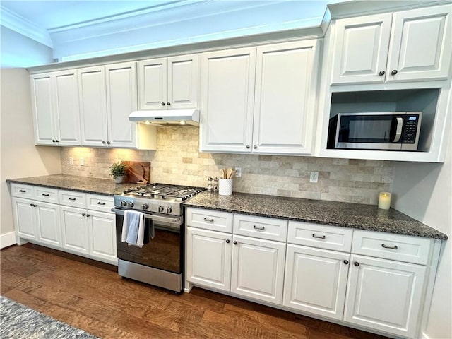 kitchen with under cabinet range hood, white cabinetry, stainless steel appliances, and backsplash