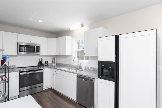 kitchen featuring a sink, dark wood finished floors, stainless steel appliances, white cabinets, and decorative backsplash