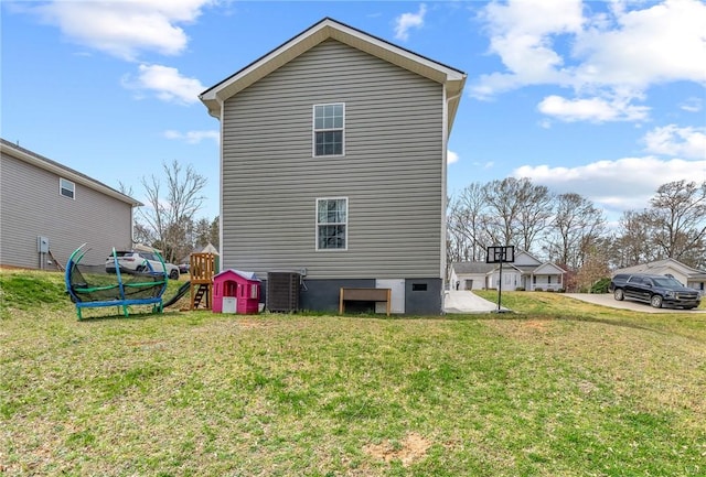back of property featuring central AC unit, a playground, and a yard