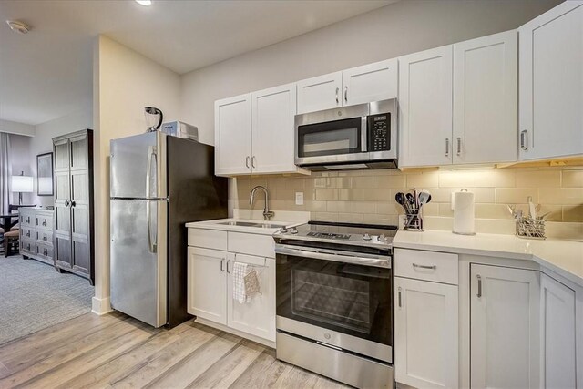 kitchen featuring light countertops, a sink, backsplash, and stainless steel appliances