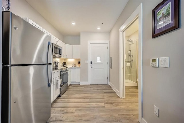 kitchen featuring light wood-type flooring, baseboards, light countertops, white cabinets, and appliances with stainless steel finishes