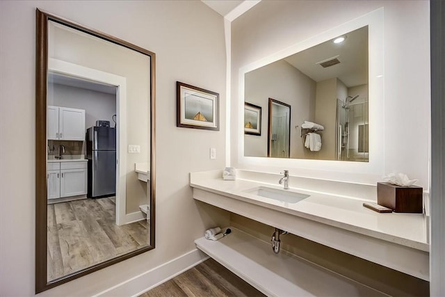 bathroom with wood finished floors, vanity, baseboards, and visible vents