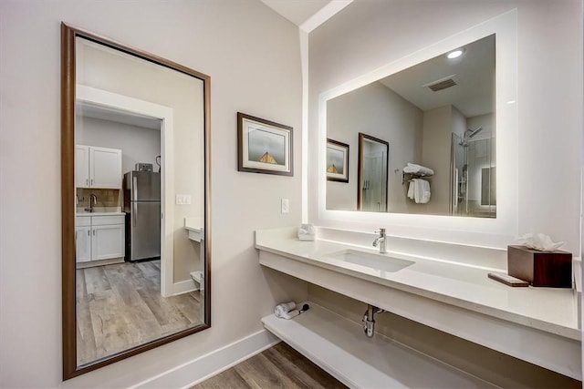 bathroom with visible vents, baseboards, vanity, and wood finished floors