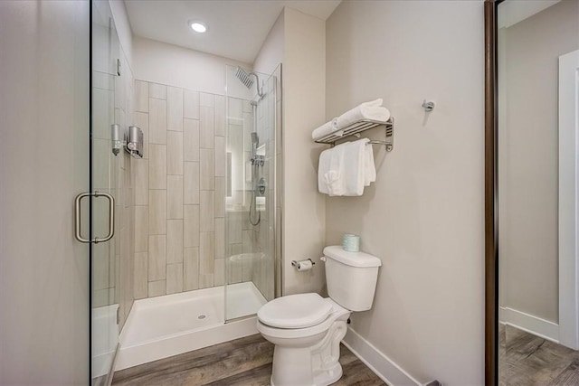 bathroom featuring a shower stall, baseboards, toilet, and wood finished floors