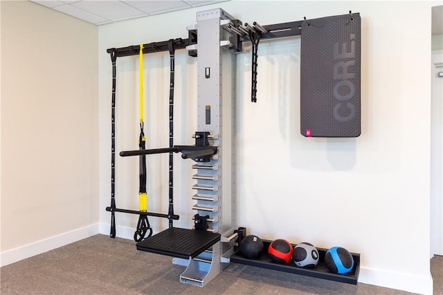 workout area featuring a paneled ceiling and baseboards