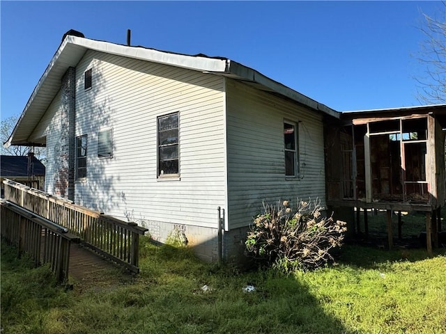 view of side of home with a sunroom and a lawn