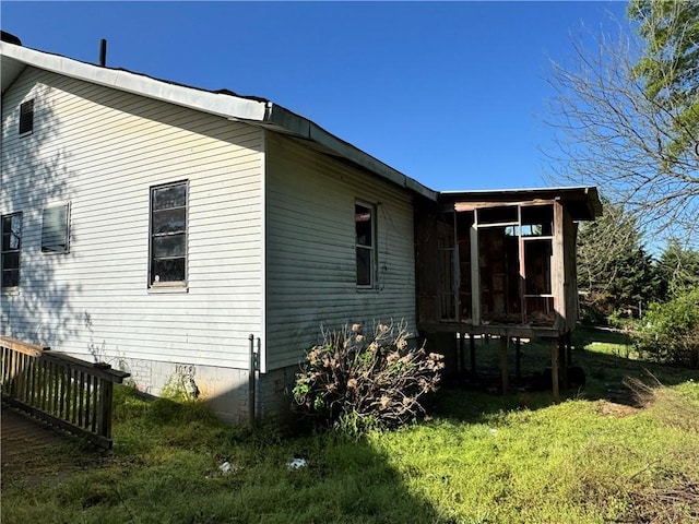 view of property exterior featuring crawl space, a sunroom, and a lawn