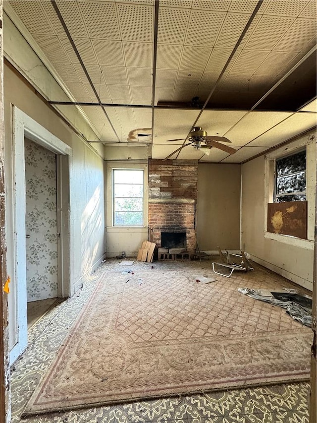 unfurnished living room featuring a large fireplace and a ceiling fan