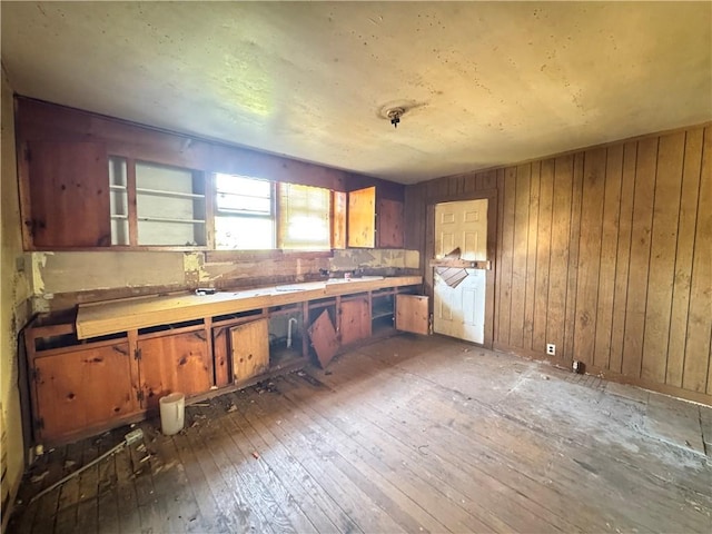 kitchen with wooden walls, backsplash, brown cabinetry, and hardwood / wood-style floors