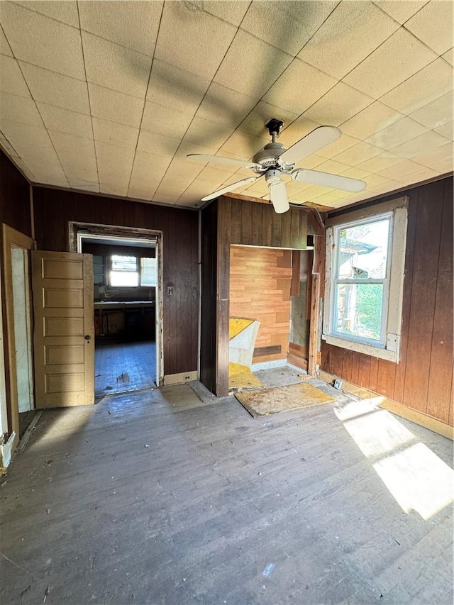 unfurnished room with wood finished floors, wood walls, and ceiling fan