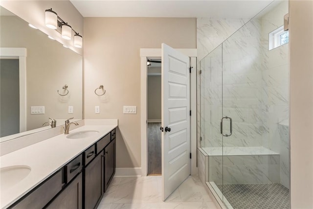 full bath featuring baseboards, a sink, double vanity, a marble finish shower, and marble finish floor