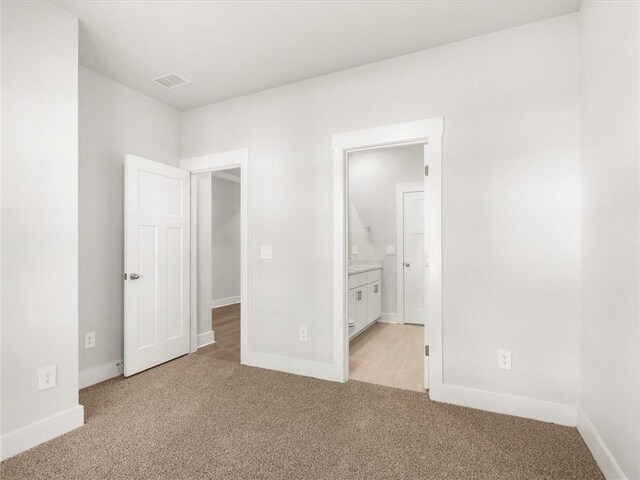unfurnished bedroom featuring light carpet, baseboards, and connected bathroom