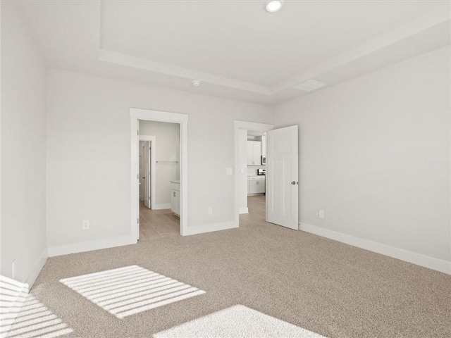 unfurnished bedroom featuring carpet flooring, baseboards, a raised ceiling, and recessed lighting