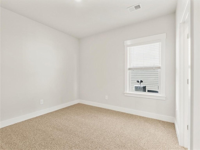 spare room featuring light colored carpet and baseboards