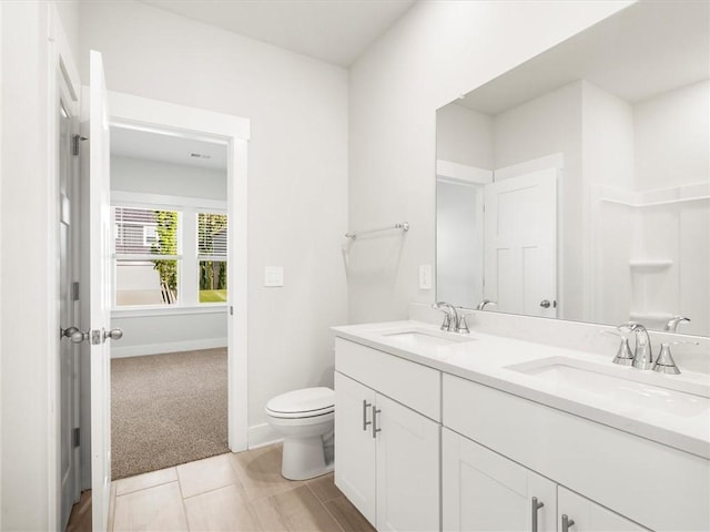 bathroom featuring double vanity, toilet, and baseboards