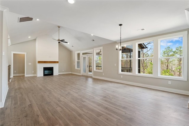 unfurnished living room featuring visible vents, a large fireplace, ceiling fan with notable chandelier, and wood finished floors