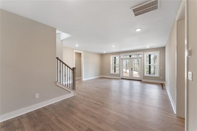unfurnished living room with visible vents, baseboards, stairway, and wood finished floors