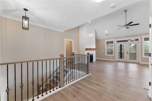 corridor featuring baseboards, ornamental molding, an upstairs landing, vaulted ceiling, and wood finished floors