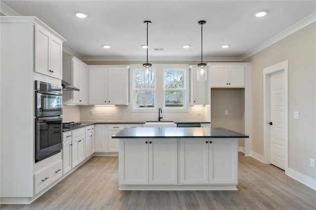 kitchen with decorative backsplash, a sink, white cabinets, and a kitchen island