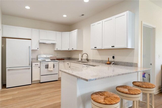 kitchen featuring white appliances, a peninsula, white cabinetry, under cabinet range hood, and a sink