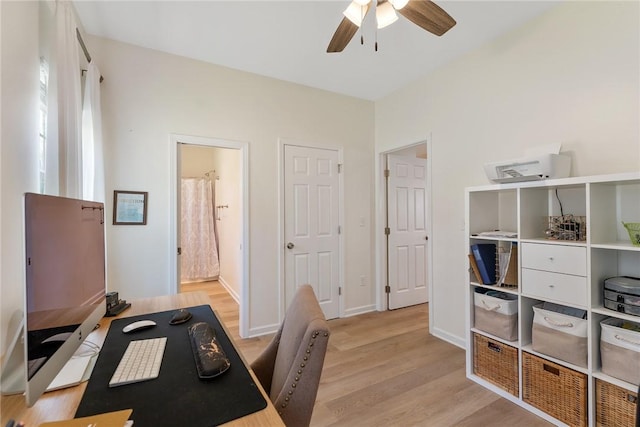 home office featuring light wood-style flooring, a ceiling fan, and baseboards