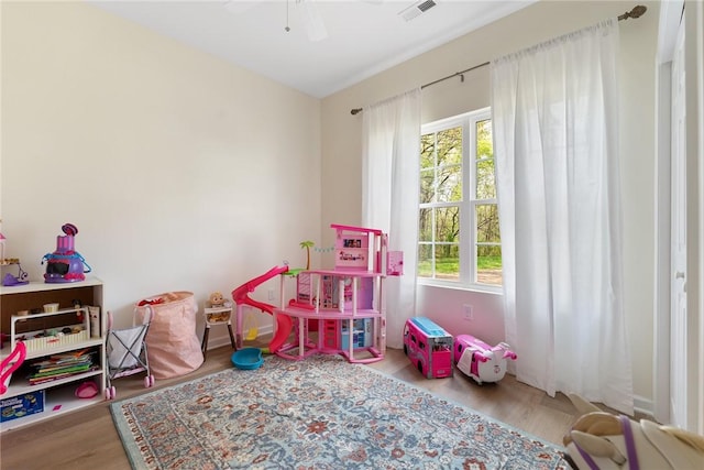 rec room with visible vents, a ceiling fan, and wood finished floors