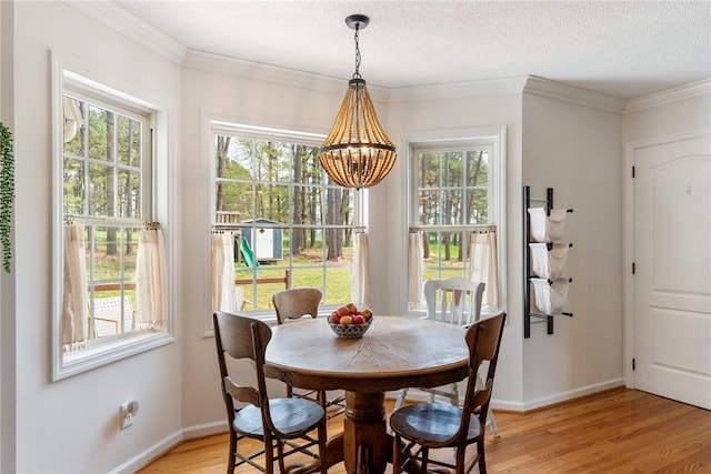 dining space featuring light wood-style flooring, a textured ceiling, a chandelier, and crown molding