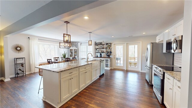 15009 Beacon Ridge Dr, Seneca, SC 29678 - kitchen featuring appliances with stainless steel finishes, a kitchen breakfast bar, white cabinetry, dark wood-type flooring, and a kitchen island with sink