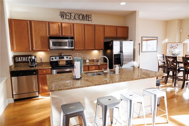 1226 Bowersville Hwy, Hartwell, GA 30643 - kitchen with a breakfast bar, light wood-style flooring, brown cabinets, appliances with stainless steel finishes, and a sink