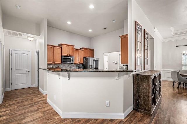 kitchen with brown cabinets, visible vents, appliances with stainless steel finishes, and a kitchen bar