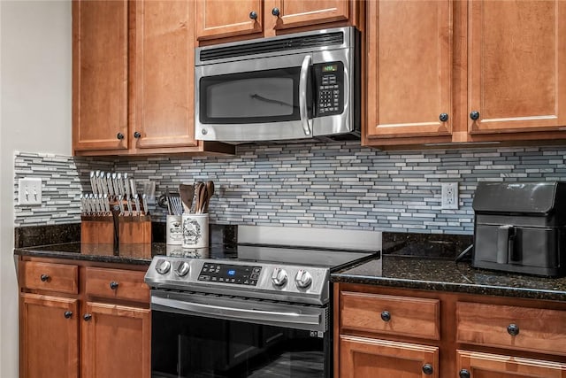 kitchen with stainless steel appliances, brown cabinets, backsplash, and dark stone counters
